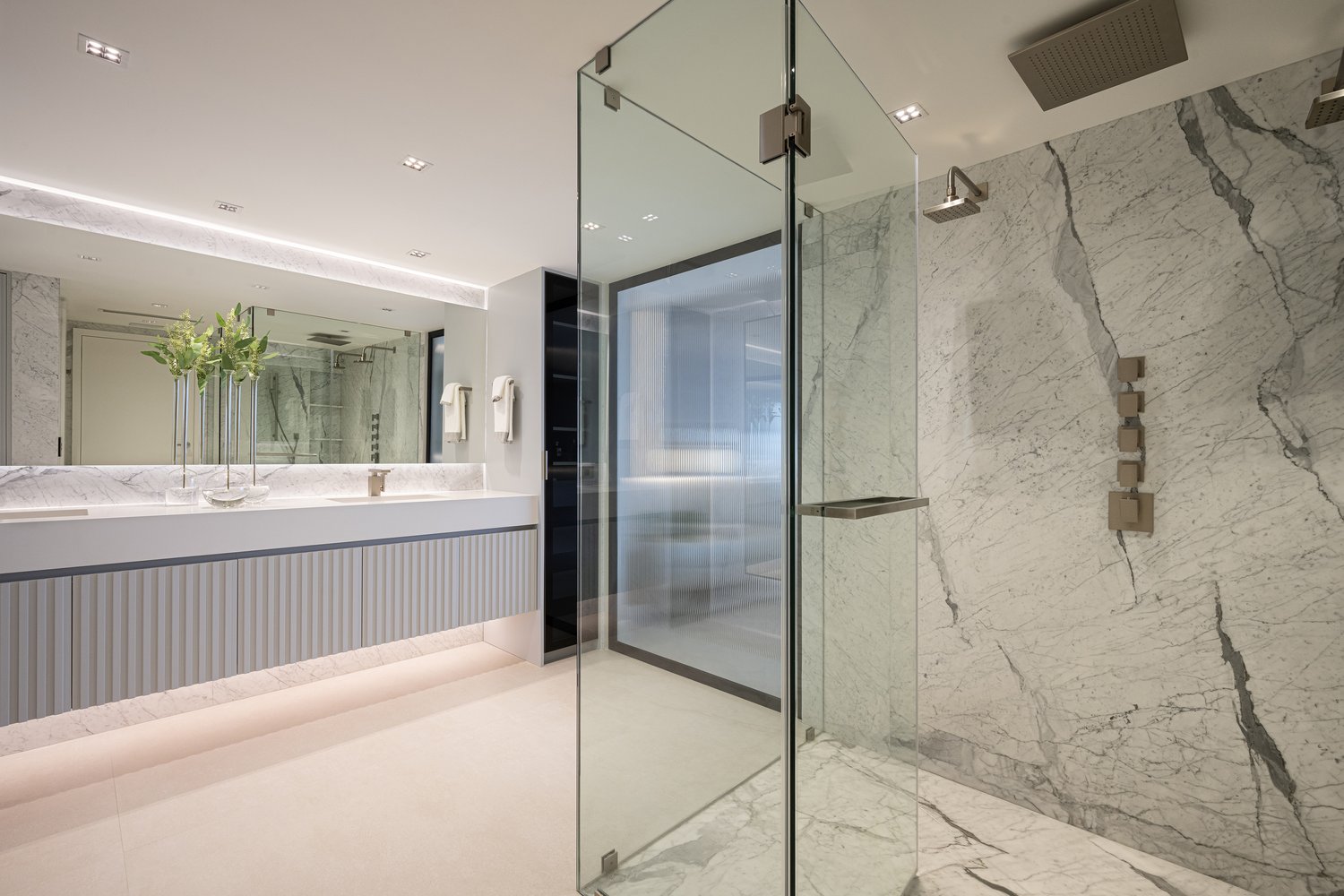 Marble walk-in shower with fluted vanity and glass enclosure