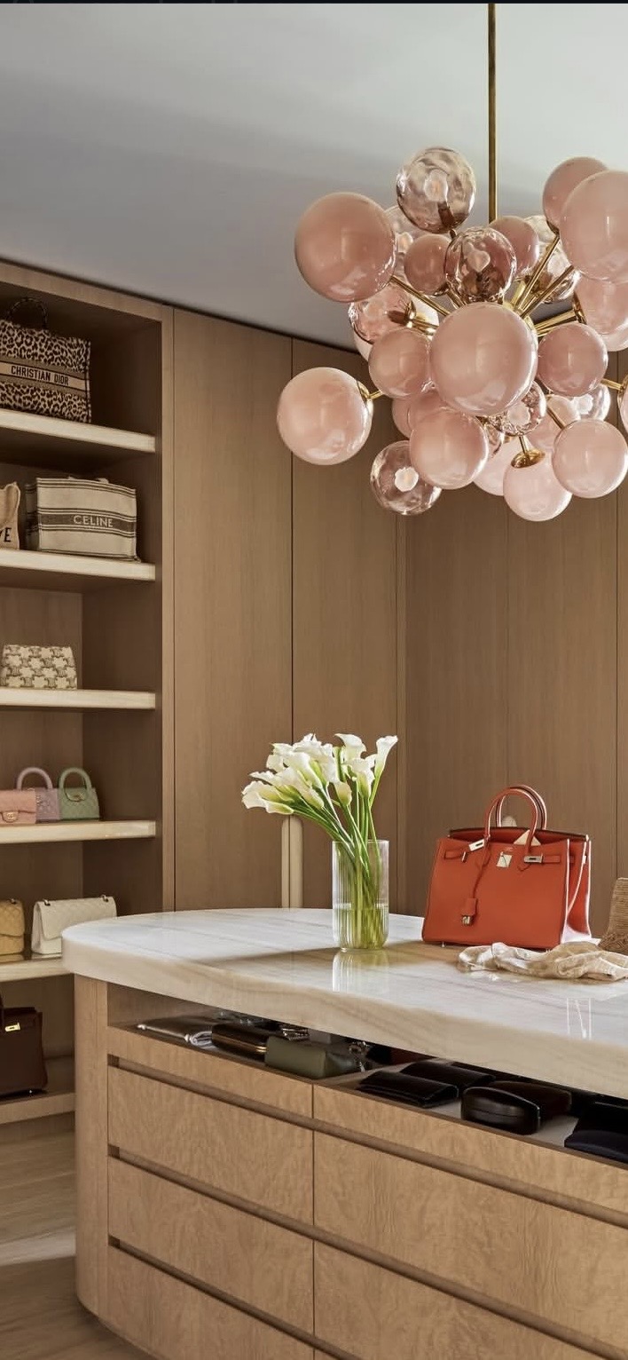 Boutique dressing room with oak island, marble top, handbag shelves and blush chandelier