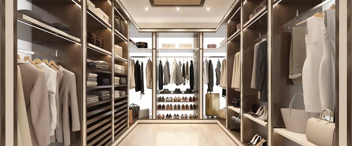 Dark wood boutique walk-in closet with illuminated shelving and shoe wall