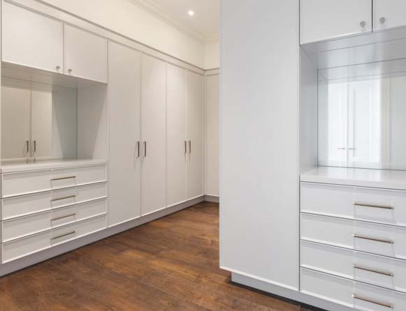 Transitional white walk-in closet with mirrored vanity nook and drawer bank