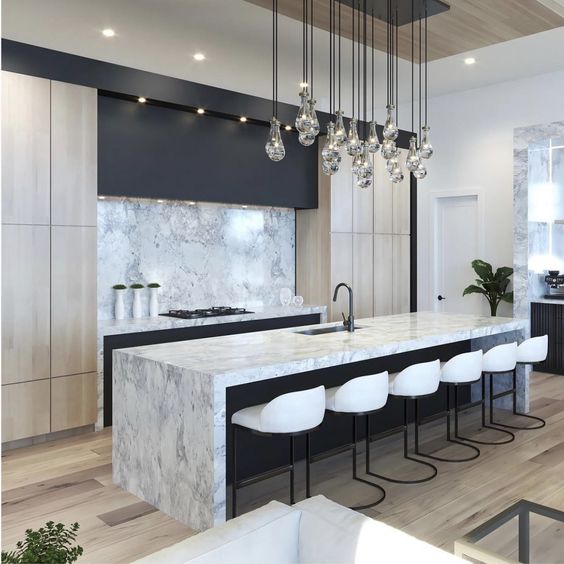 Black and blonde modern kitchen with marble waterfall island and glass pendant cluster