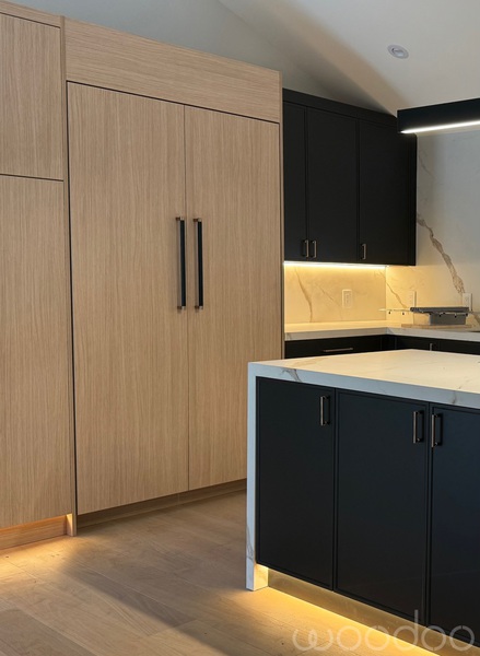 Black cabinetry with white oak paneling and marble backsplash
