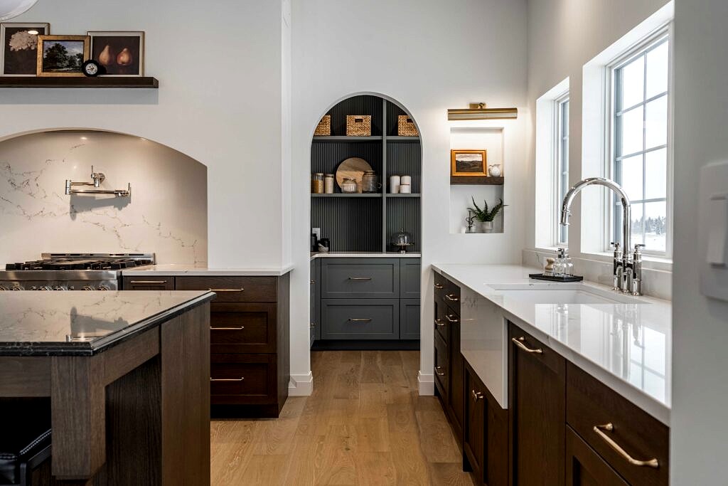 Kitchen with arched pantry nook, dark cabinetry and farmhouse sink