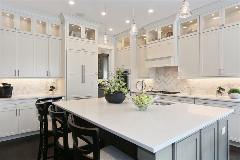 Transitional white kitchen with glass-front upper cabinets and marble herringbone backsplash