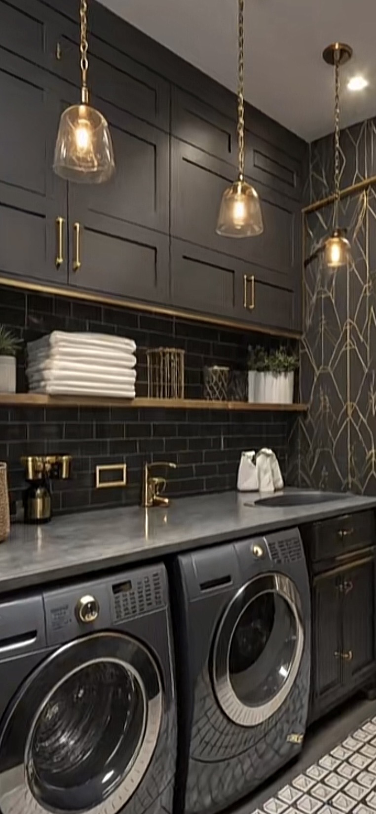 Black and brass laundry room with dark subway tile and glass pendants