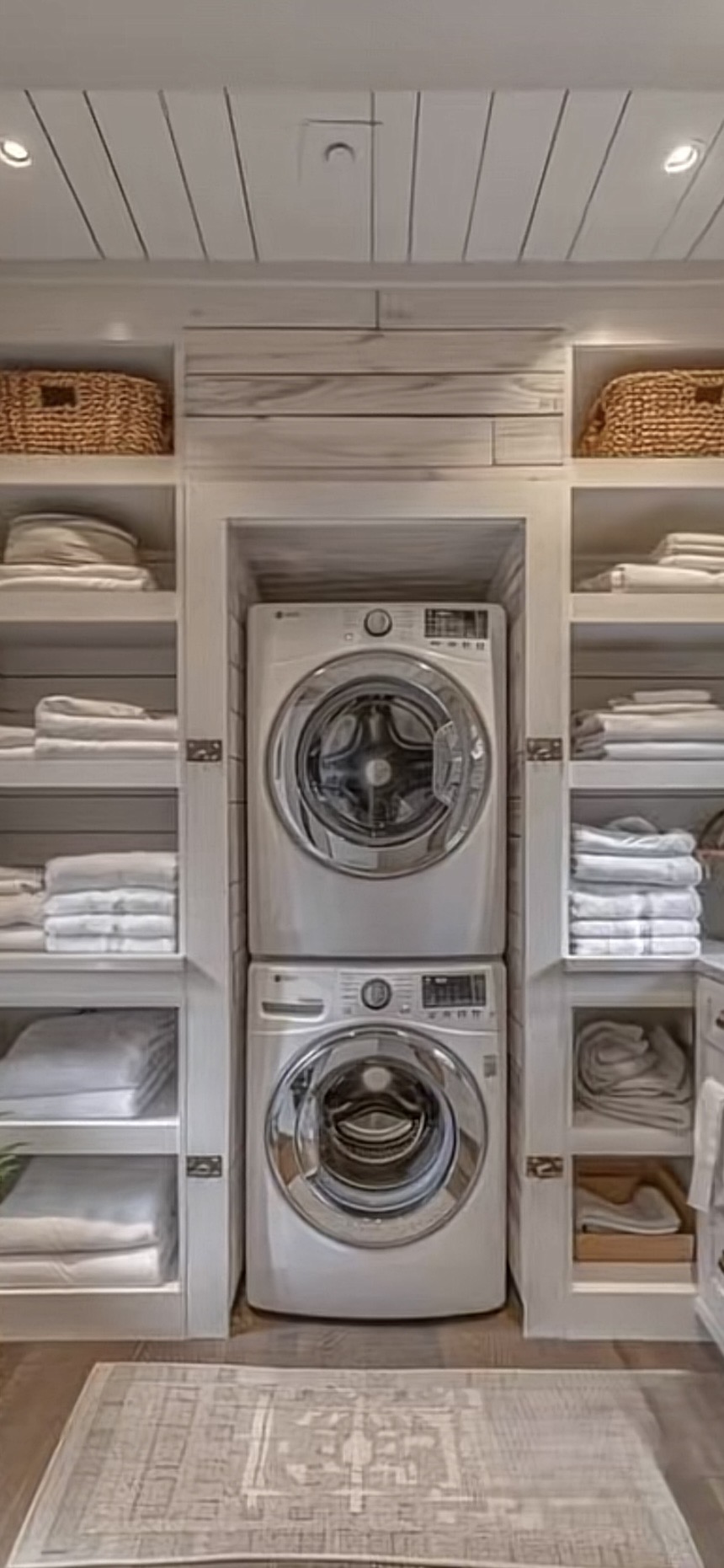 White laundry room with stacked washer dryer, shiplap surround and woven storage baskets