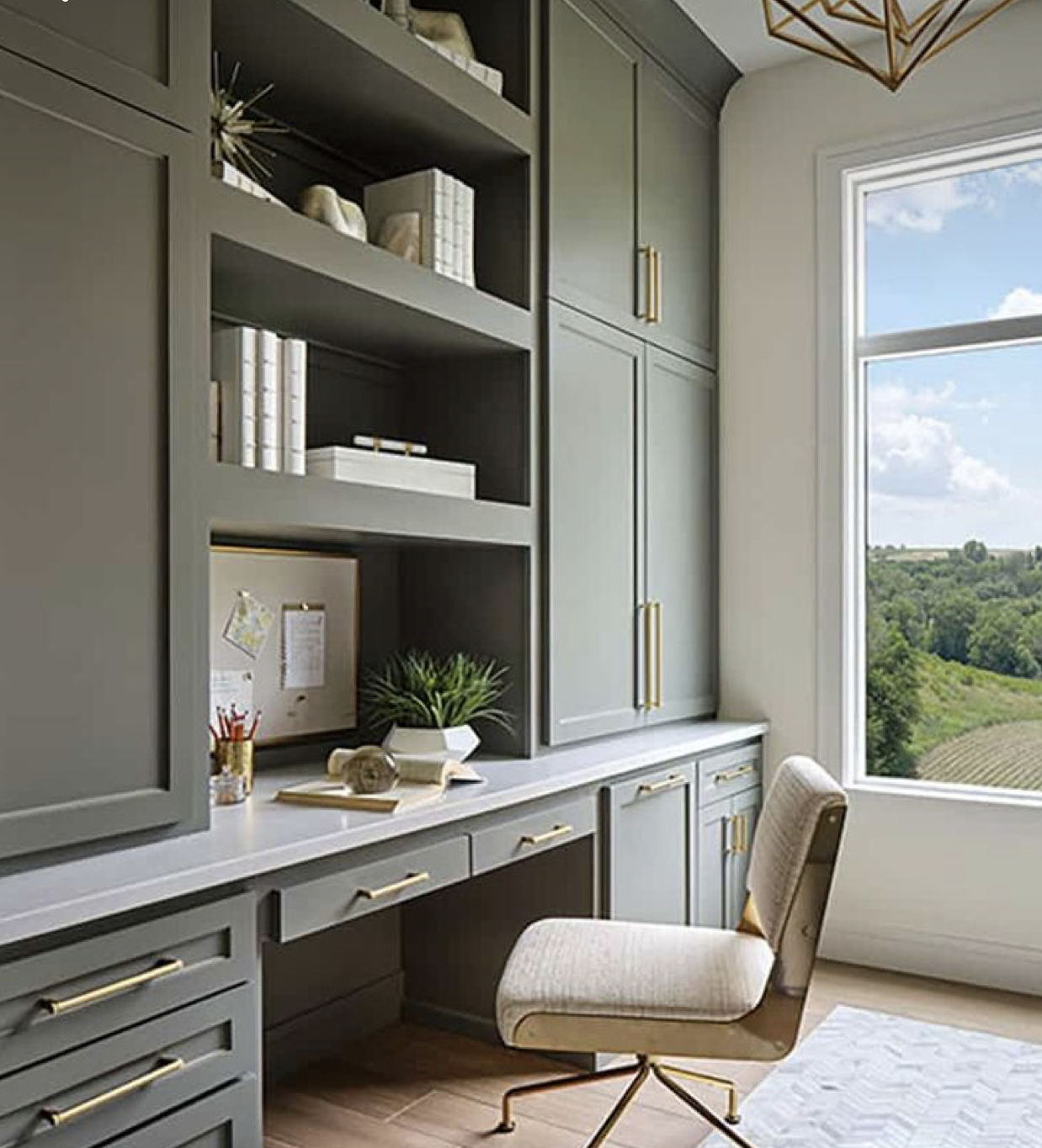 Sage green built-in home office desk with brass hardware and countryside view